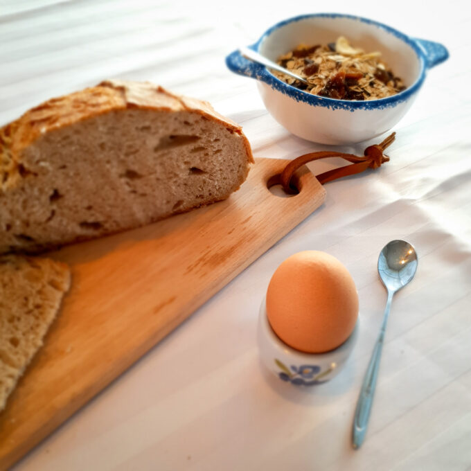 Planche à découper en bois poru lel petit déjeuner avec du pain, un oeuf à la coque et des céréales