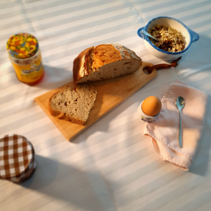 Planche à découper en bois poru lel petit déjeuner avec du pain, un oeuf à la coque, de la confiture, du miel et des céréales